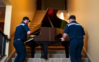 Piano movers skillfully transporting a grand piano with care and expertise.